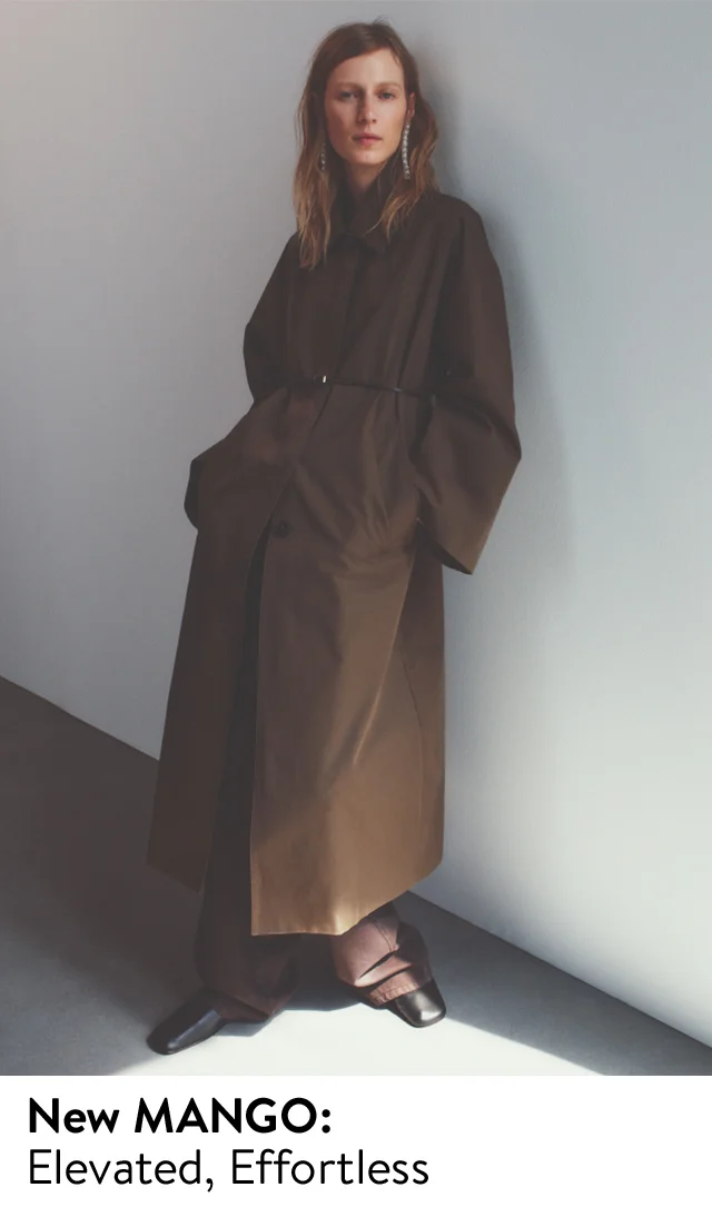 A woman wearing a trench coat with brown jeans and black leather shoes.