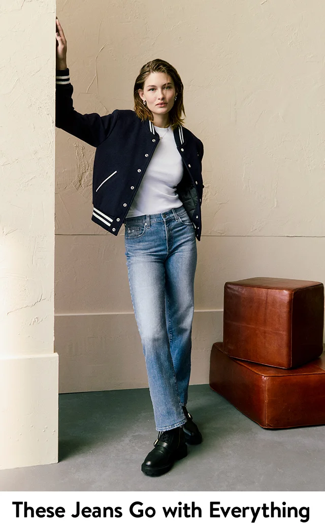 A woman wearing straight-leg jeans with a white T-shirt and a varsity jacket.
