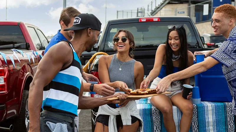 A group tailgating enjoying pizza out the back of their truck