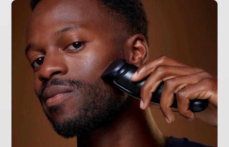 A man trimming his beard with King C. Gillette Beard Trimmer