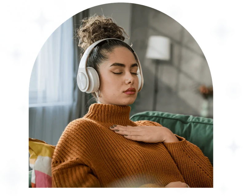 A young woman practices guided meditation in the living room on her sofa