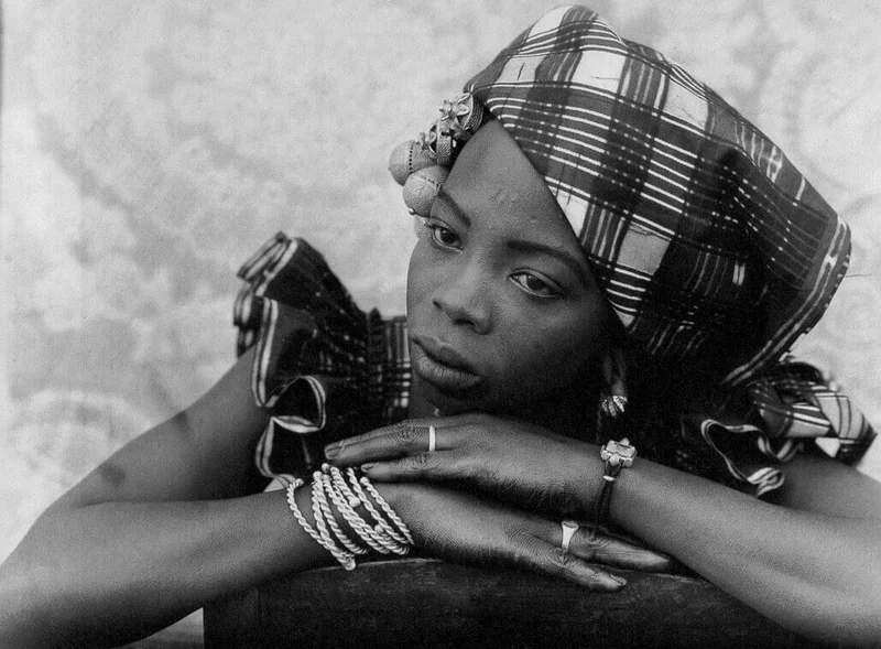 A photograph of a woman with her head resting on her hands