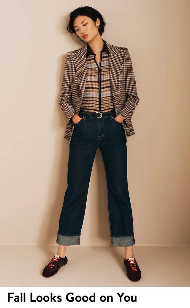 A woman wearing a striped polo, checked jacket, jeans and sneakers; the jacket, polo, jeans and sneakers.