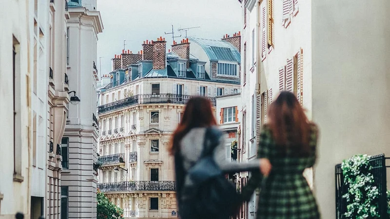 Image description: Two friends walking on a street in Paris.