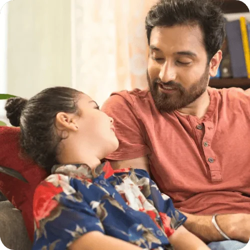 A dad talking to his daughter on the couch about her day at school