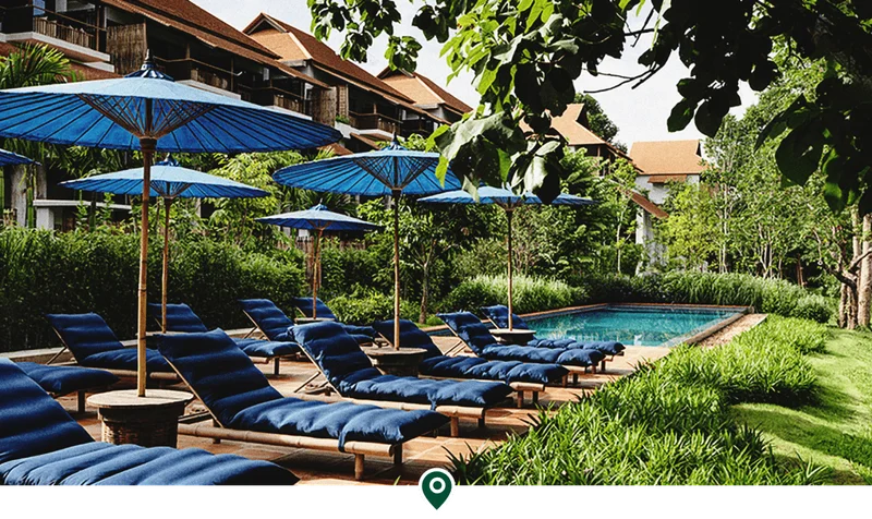 Image Description: Two rows of sun loungers with blue cushions beside an outdoor pool in Raya Heritage, a five-star hotel in Chiang Mai