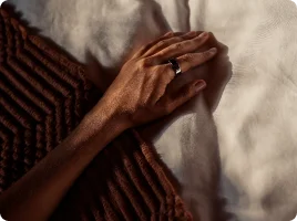 Left hand on bed wearing Oura Ring