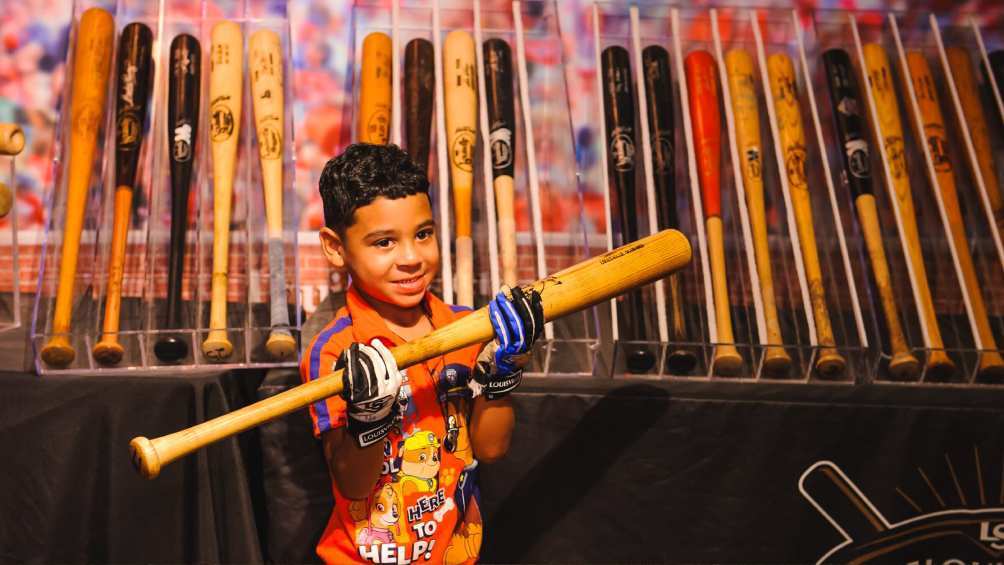 Image description: Boy holding up baseball bat at Louisville Slugger Museum & Factory.