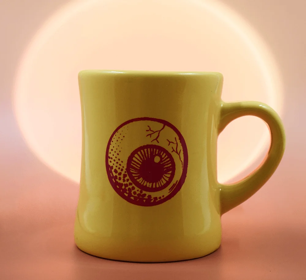 👁️ ️Seer of Sights Mug ☕️ This hefty, chonky unit of a diner mug absolutely *insists* on watching you enjoy your morning cup in a supportive, delightfully chaotic way.  Bright yellow body, neon pink eyeball and logo, 12 oz capacity.  A perfect companion to your morning ritual or an excellent “pair it with beans” gift moment. ☕️ Summon the Seer of Sights Mug ☕️
