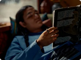 Person lying in couch looking at a tablet wearing Oura Ring on right hand
