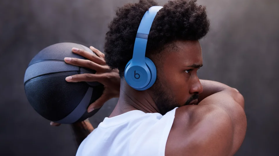 Man wearing Beats Solo 4 headphones and holding a basketball.
