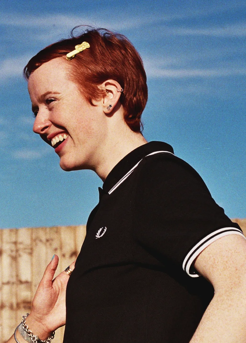 A white female wearing a Black Twin Tipped Fred Perry Shirt