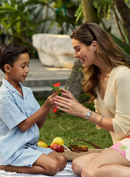 A woman and child outdoors with a flower.