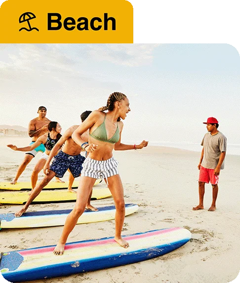 Image description: Four people standing on surfboards on the beach. An umbrella icon next to the word “Beach” is at the top of the image.