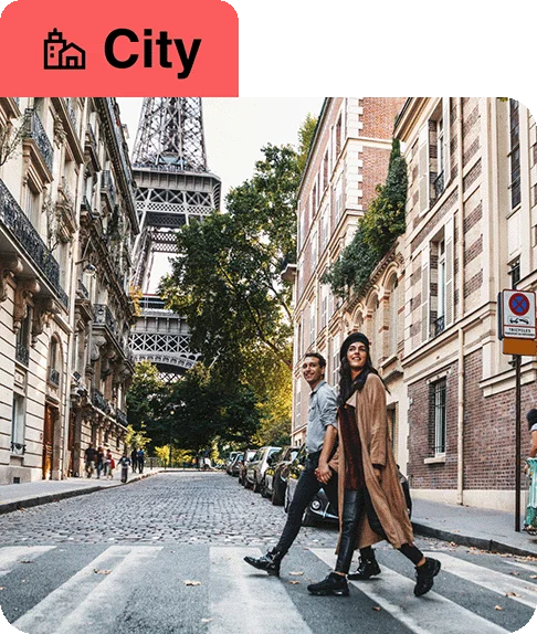 Image description: Two people crossing the street in front of the Eiffel Tower. A building icon next to the word “City” is at the top of the image.