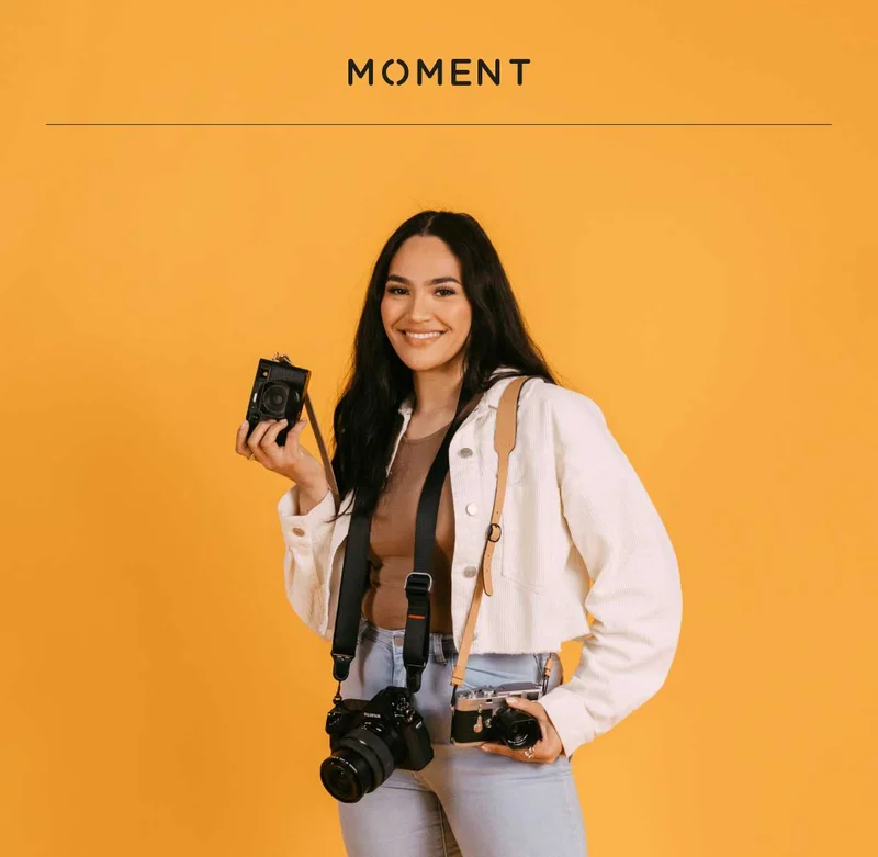 Image of woman smiling while holding several cameras.
