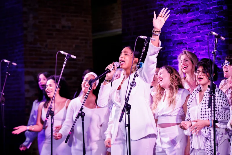 A choir dressed in white singing on a stage