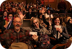 Attendees at a Festival screening with their hands up and cheering.