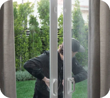 Burglar entering home through door with Arlo All-in-One Sensors.