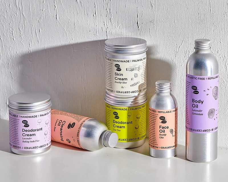 A bunch of metal bottles sitting on a textured white background with a rainbow of colors on their labels