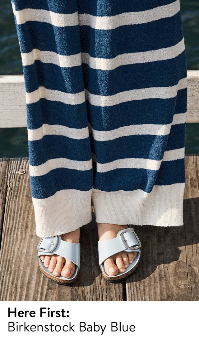 A woman wearing blue Birkenstock sandals with a striped shirt and pants.