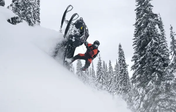 Lynx rider standing on their snowmobile