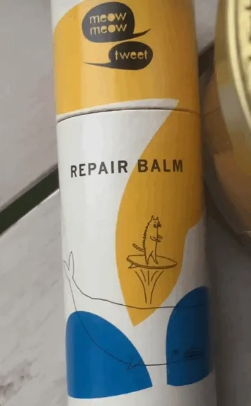 A medium brown skinned person with long wavy black hair applies our paper tubed repair balm to their lips