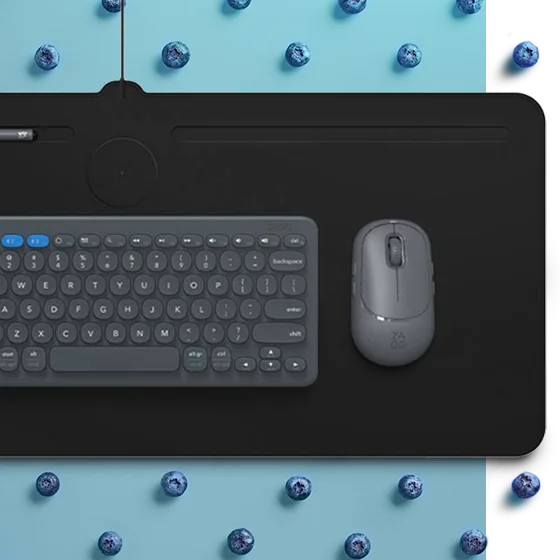 Wireless Charging Desk Mat on a blue background surrounded by blueberries