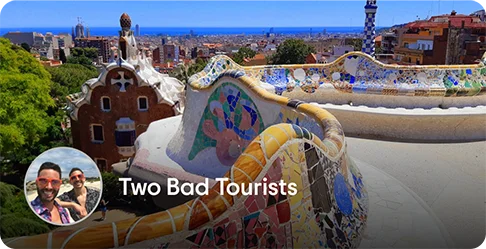 Image Description: A wall with a colorful mosaic overlooking a city. A profile photo of two people wearing sunglasses and the name Two Bad Tourists is on the bottom left corner of the image.