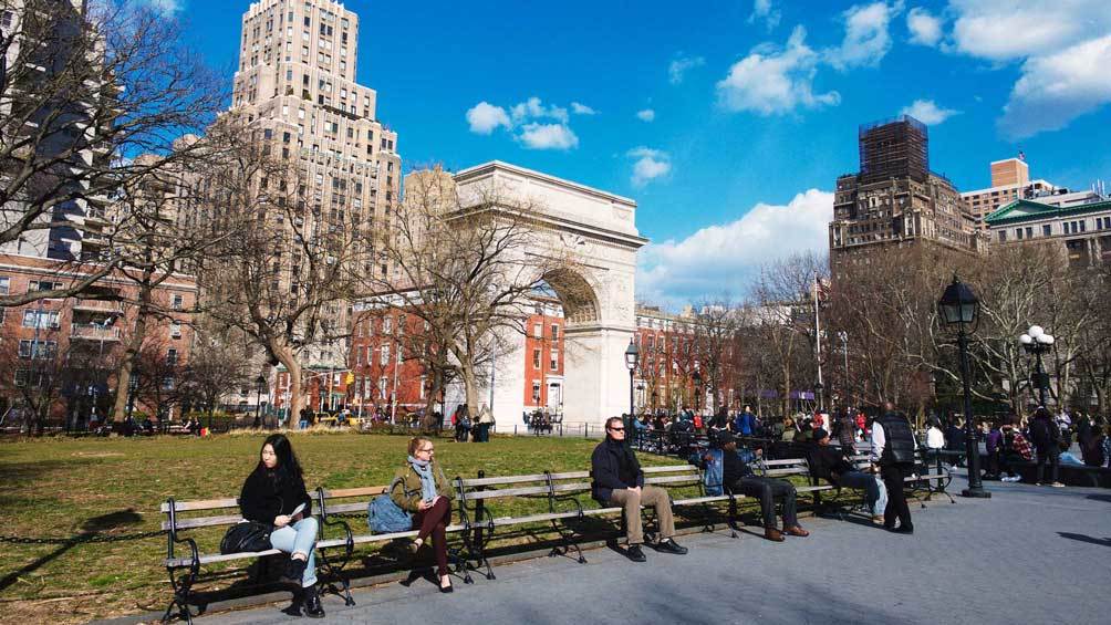 Image description: People sit on benches at Washington Square Park.
