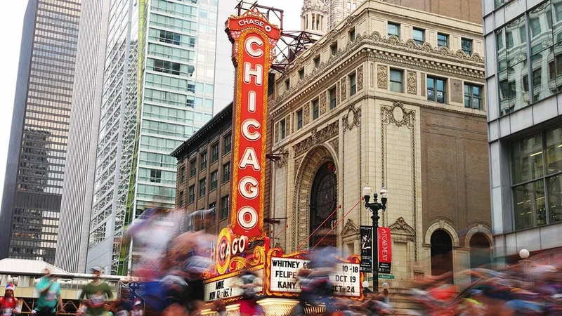 Image description: Marathon runners run past the Chicago Theatre.