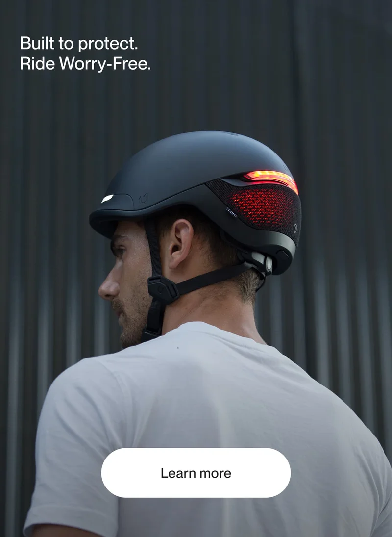 Man riding with a UNIT 1 smart helmet at sunset, showcasing integrated rear lights and sleek, urban-ready design.