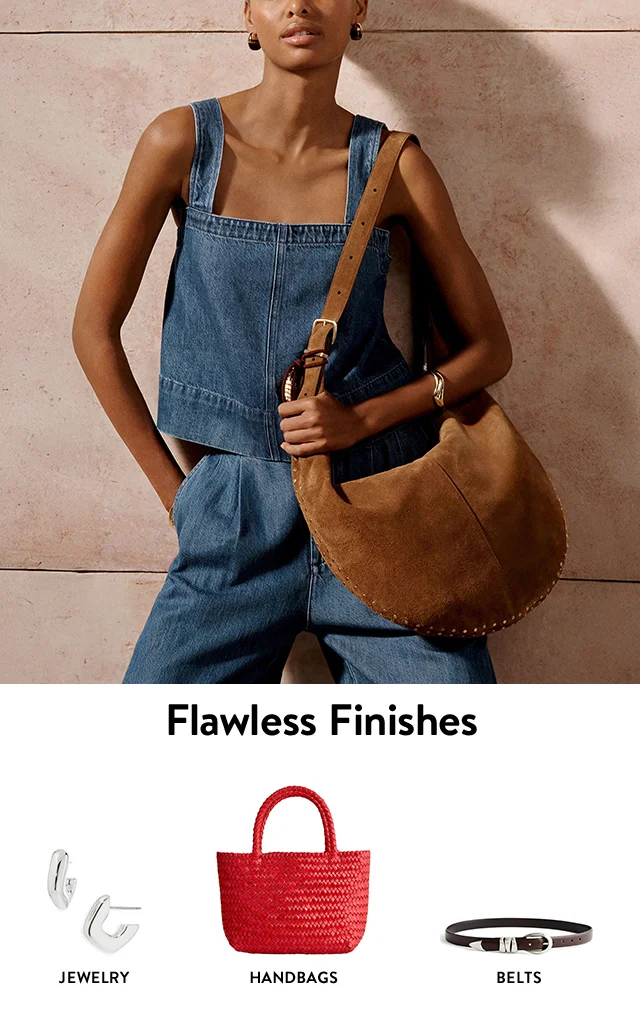 A woman holding a brown shoulder bag. Silver hoop earrings, a red tote and a leather belt.