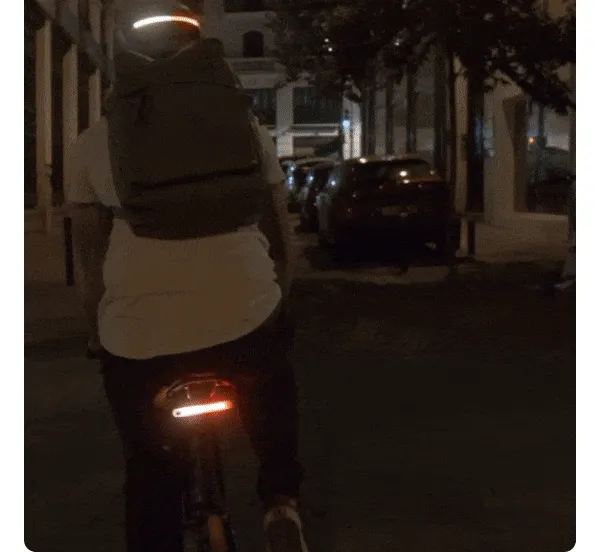 GIF of a cyclist riding at night using synchronized helmet and rear Smart Light signals.