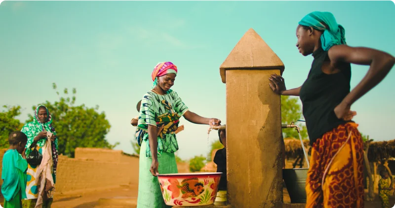 Women in Mali talk while filling containers with clean water.