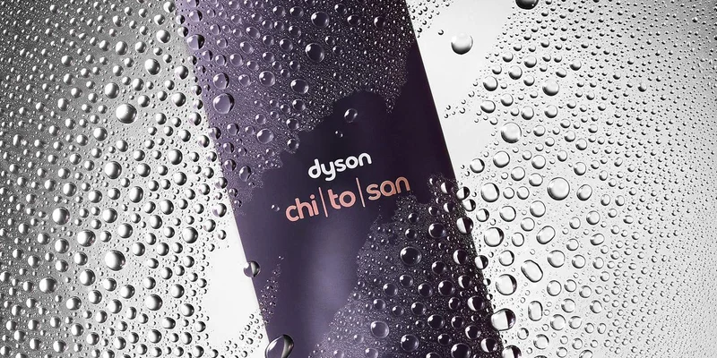 Dyson Chitosan Multi-use styling spray behind spray droplets on a glass pane