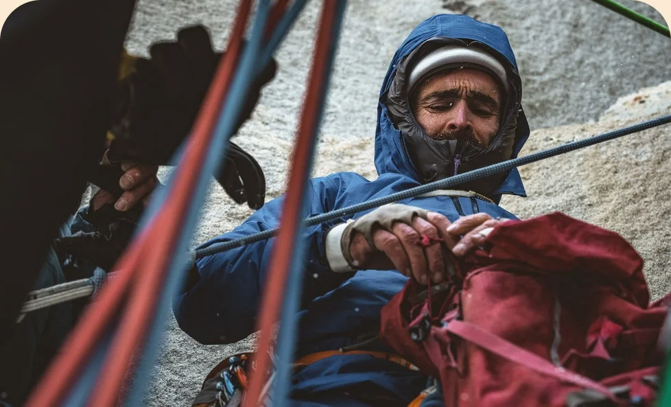 A person on a climb putting things in a backpack.