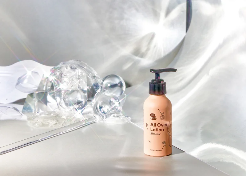 A pink bottle sits in refracted light a crystal baubles