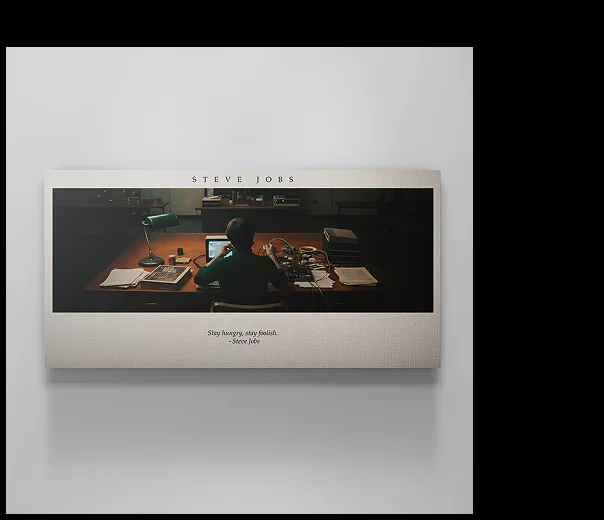 Canvas art showing Steve Jobs sitting at his desk in a dimly lit workspace surrounded by papers and early Apple prototypes. The top reads “STEVE JOBS,” with the quote below: “Stay hungry, stay foolish.” — Steve Jobs. Canvas art showing Steve Jobs sitting at his desk in a dimly lit workspace surrounded by papers and early Apple prototypes. The top reads “STEVE JOBS,” with the quote below: “Stay hungry, stay foolish.” — Steve Jobs.