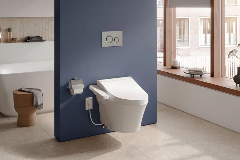 A TOTO C2 WASHLET displayed against a blue wall in a bright open concept bathroom