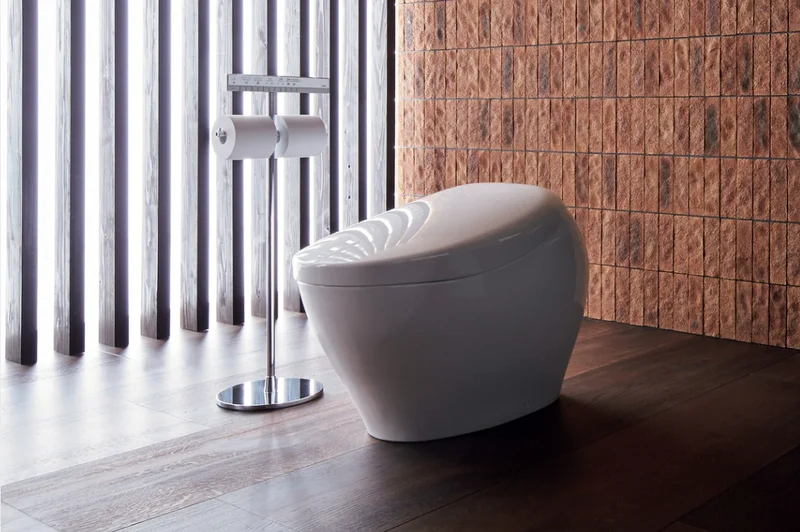 A TOTO NEOREST NX 1 smart toilet displayed against red brick tile on dark wood flooring