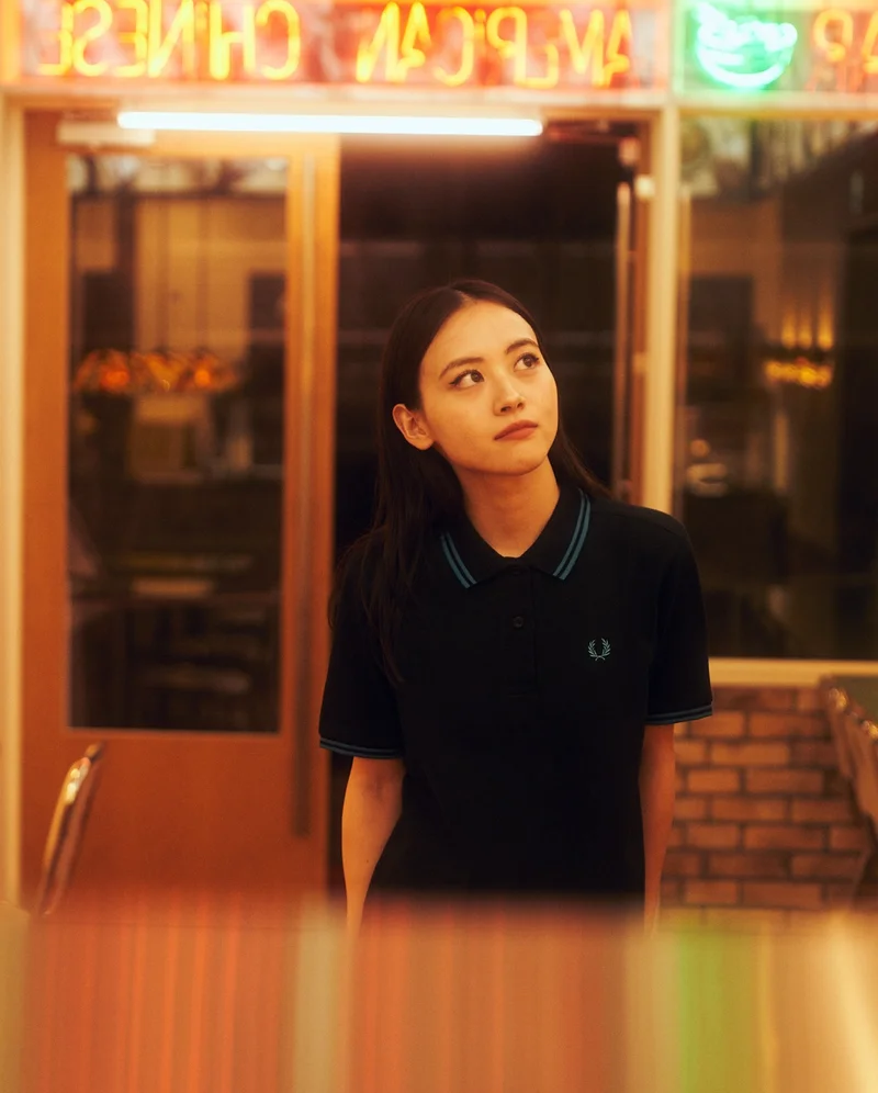 Asian model wearing a black fred perry polo shirt