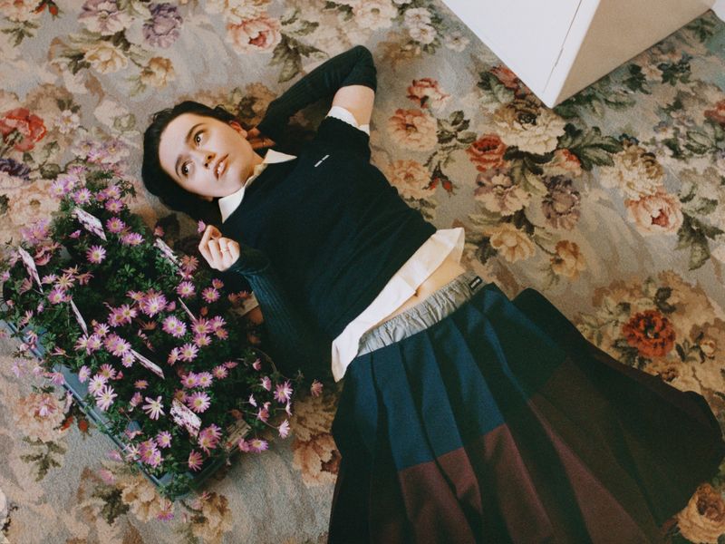 Image may contain: Aimee Lou Wood, Face, Head, Person, Photography, Portrait, Clothing, Skirt, Plant, and Potted Plant