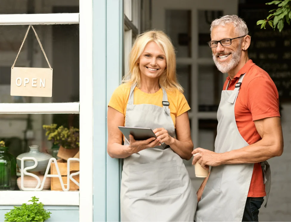 A couple of restaurant owners standing outside of their shop