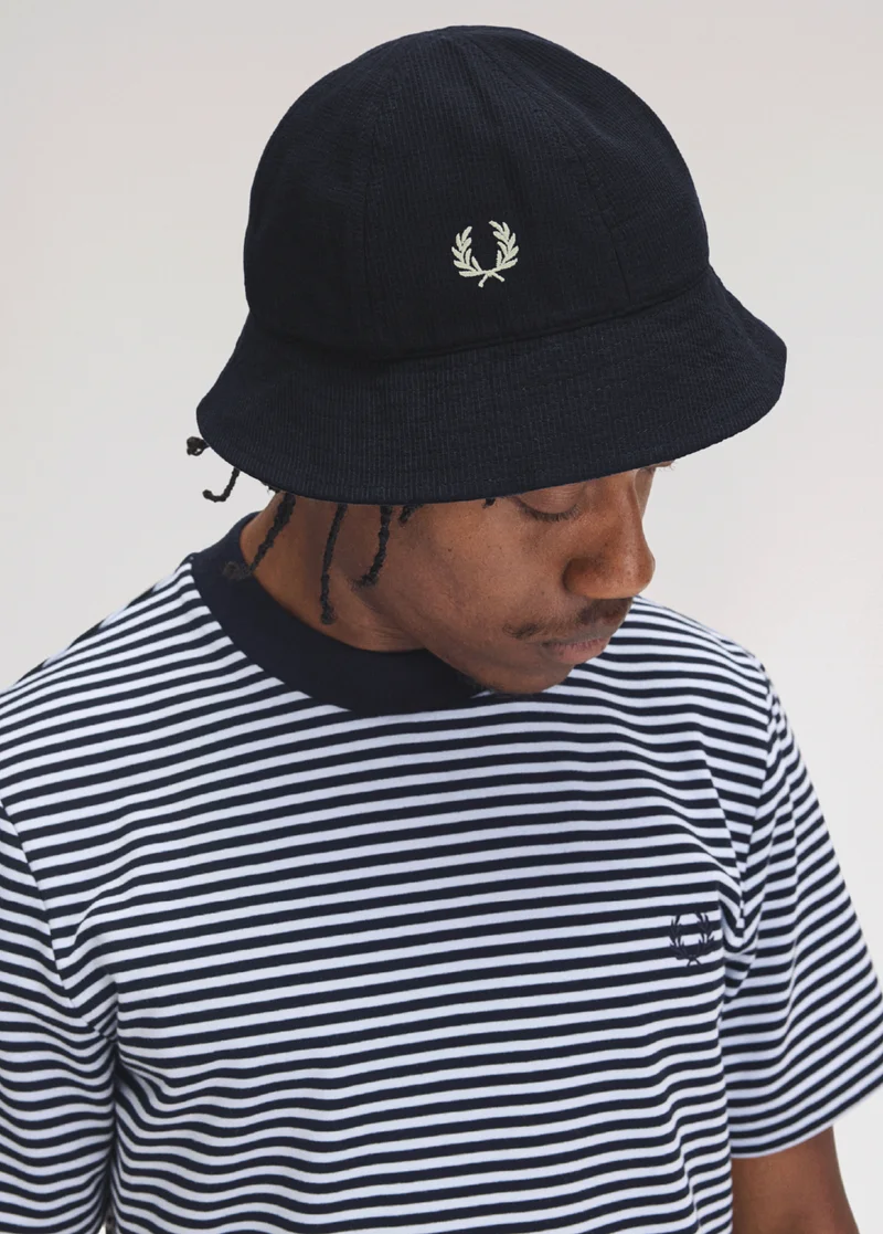 Man wearing stripey Fred Perry T-Shirt with a Fred Perry Bucket Hat