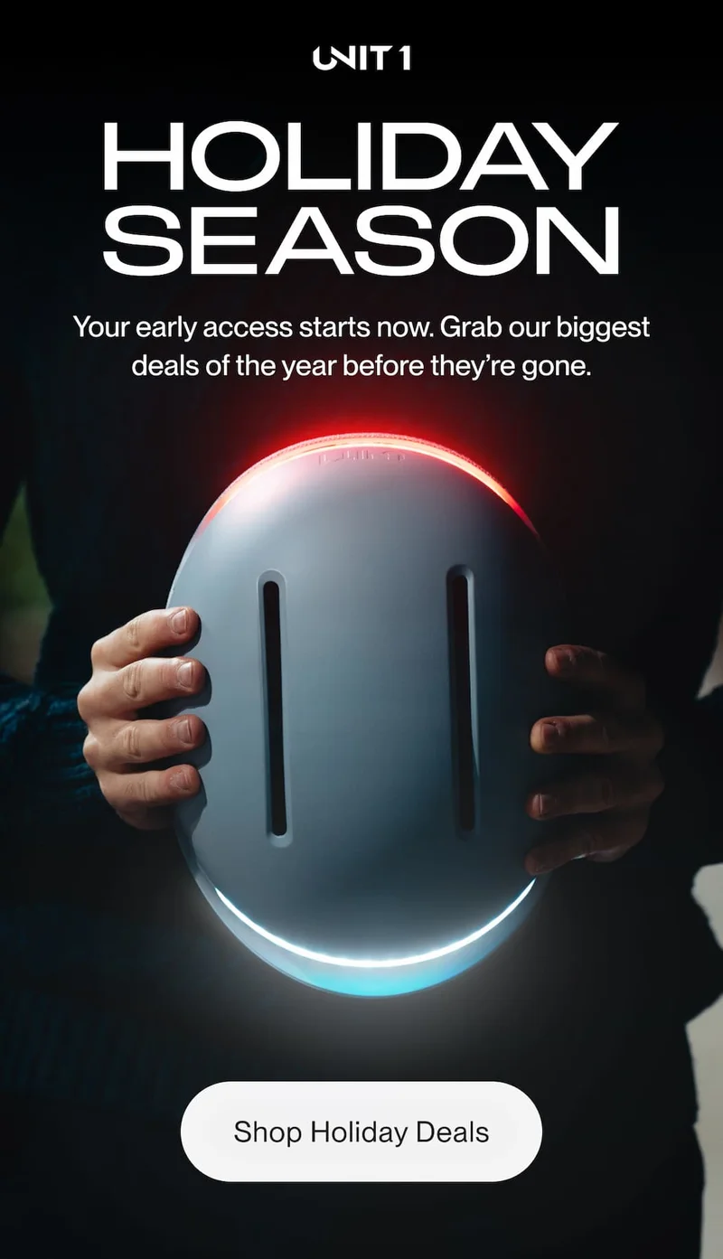 Person holding a UNIT 1 smart helmet glowing red and white lights in a dark scene — announcing once-a-year Holiday deals and early access.