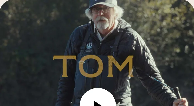 Tom Derry stands in a river with his wading staff and steelhead rod.