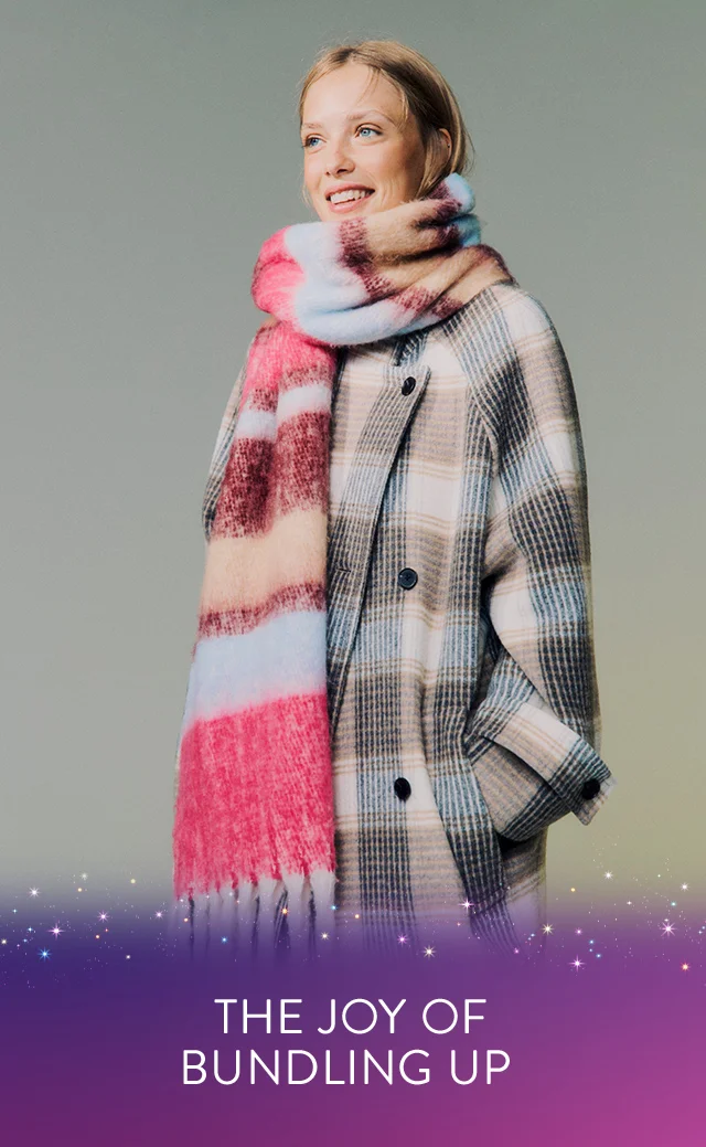A woman wearing a plaid coat with an oversized multicolored scarf.
