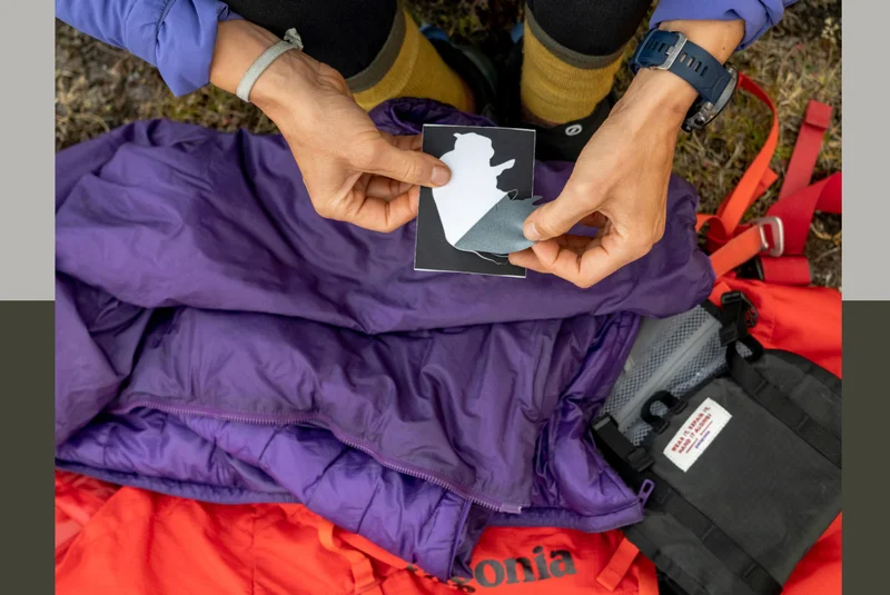 A person peels off a repair patch to put on their puffy jacket.