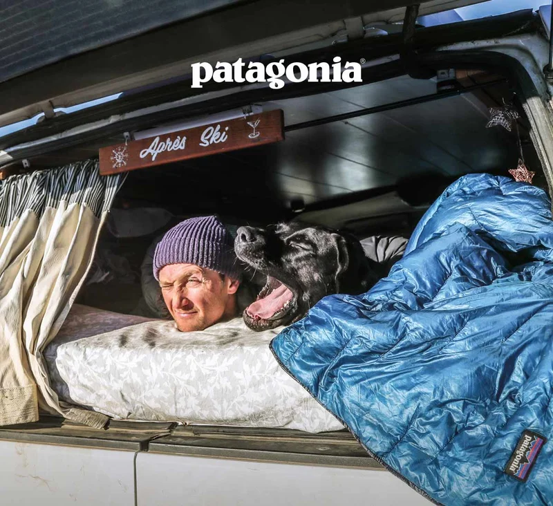 Patagonia. A dog yawns in the face of a person sleeping in the back of their truck.
